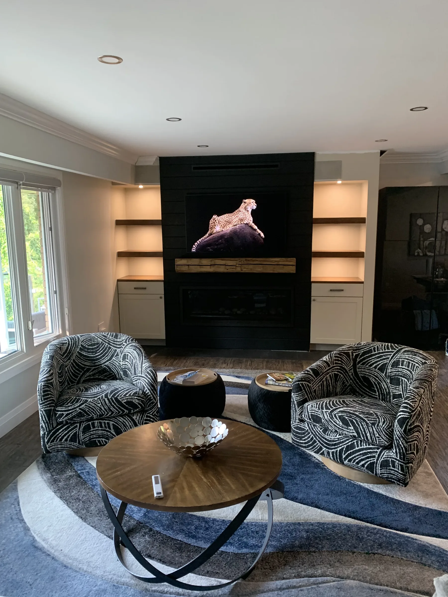 Black cabinet fireplace with sculpted art, warm interior lighting, and blue armchairs